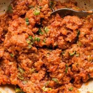 Spicy tuna with green onions in a bowl, mixed with a fork.