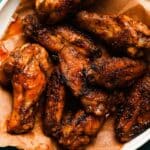 Grilled chicken wings with Old Bay brown butter glaze on parchment paper.