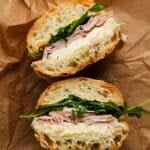 Jambon beurre sandwich with sliced ham, butter, and greens on crusty bread.