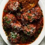 Italian meatballs in marinara sauce, topped with grated cheese and herbs.