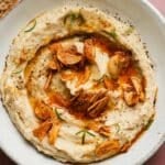 Creamy white bean dip with crispy garlic and fresh rosemary garnish.