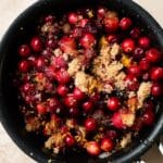 Cranberries with brown sugar and orange zest in a black pot.