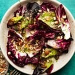 Radicchio salad with chopped hazelnuts and chives on a ceramic plate.