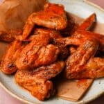 Plate of spicy baked buffalo wings with a light speckled glaze.