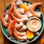 Plate of shrimp with Old Bay mayo and lemon wedges on ice.