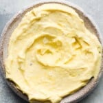 Creamy garlic aioli in a textured bowl on a gray surface.