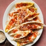 Endive salad topped with harissa breadcrumbs and grated cheese on a white plate.