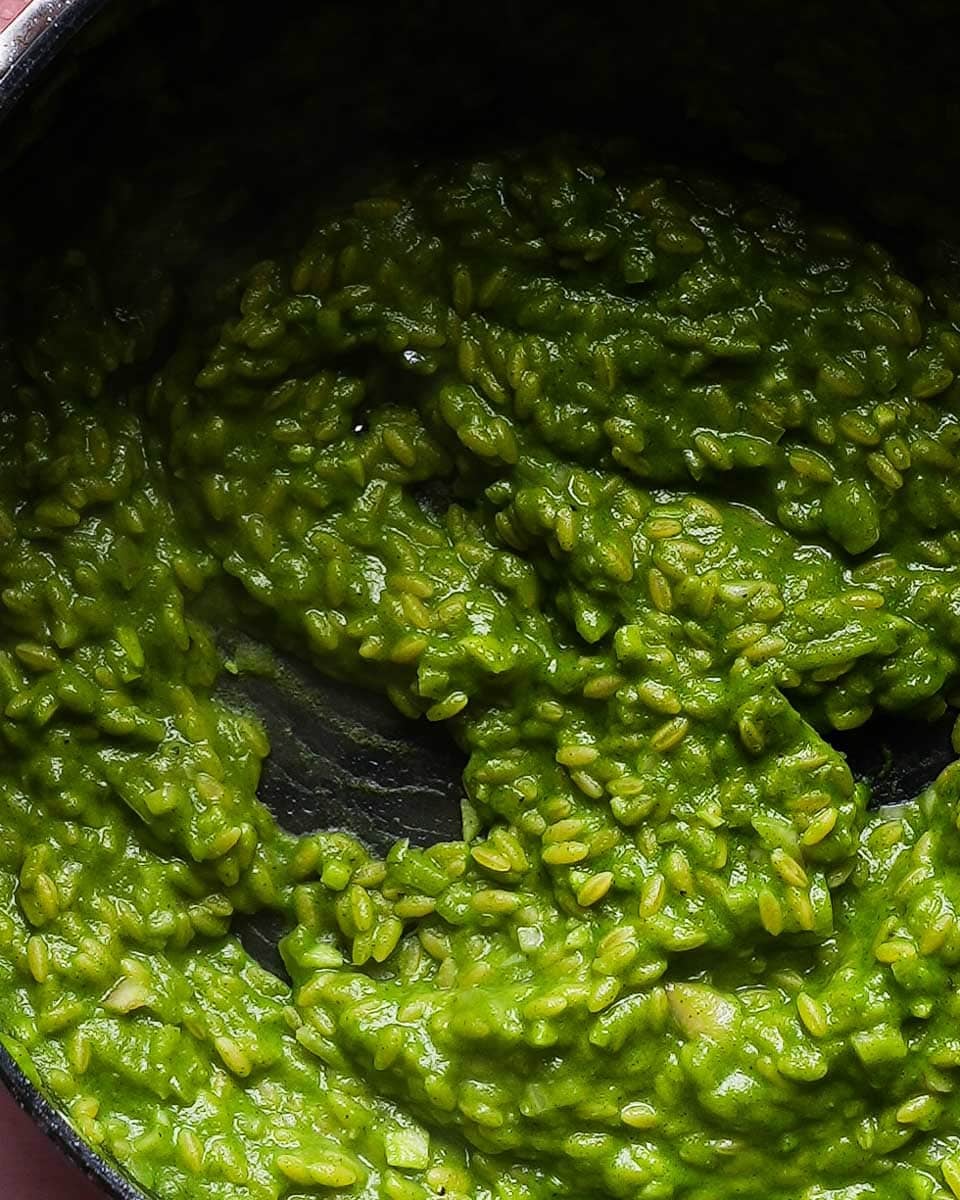 Creamy green pea and mint orzo risotto in a pan.