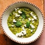 A bowl of pea and mint orzo risotto with feta cheese garnish.