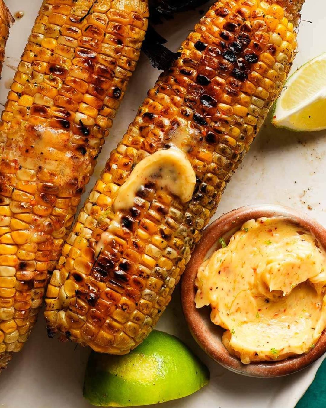 Grilled corn with Tajin lime butter, served with lime wedges.