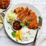 Plate of chicken katsu, rice, shredded cabbage, lemon wedges, and dipping sauce.