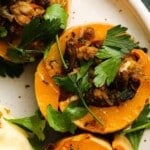 Stuffed squash garnished with fresh parsley and savory filling on a white plate.