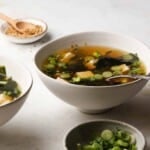 Bowl of sesame miso soup with tofu, seaweed, and green onion garnish.