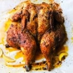Roasted chicken seasoned with mustard and paprika, served with lemon wedges.