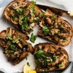 Toasted bread topped with sautéed mushrooms and fresh herbs, served with lemon wedges.