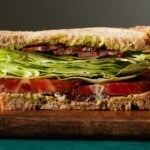 BLT sandwich with lettuce, tomatoes, bacon, and basil mayo on rustic bread.