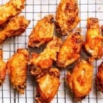 Golden, crispy chicken wings cooling on a metal rack.