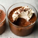 Rich chocolate mousse topped with whipped cream and chocolate shavings in a glass.