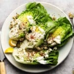 Fresh salad with Gorgonzola dressing, herbs, and lemon wedges on a plate.
