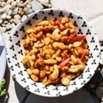 Bowl of Thai-style spicy cashew peanuts with red onions on a patterned dish.