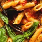 Penne pasta with tomato sauce, fresh basil, and a black spoon.
