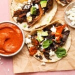 Mushroom tacos with avocado, feta, cilantro, and a side of red sauce.