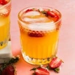 Vibrant fruit cocktail with ice, garnished with strawberries and small flowers.
