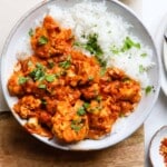 Cauliflower tikka masala with rice, garnished with fresh cilantro in a bowl.