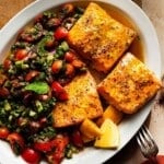 A platter of grilled salmon with Shirazi salad and lemon wedges.