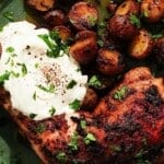 Tandoori chicken and roasted potatoes with yogurt, garnished with chopped cilantro.