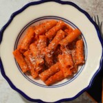 Rigatoni pasta in vodka sauce, sprinkled with parmesan cheese in a bowl.