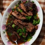 A tender, slow-cooked brisket sliced and covered in a rich, flavorful sauce.