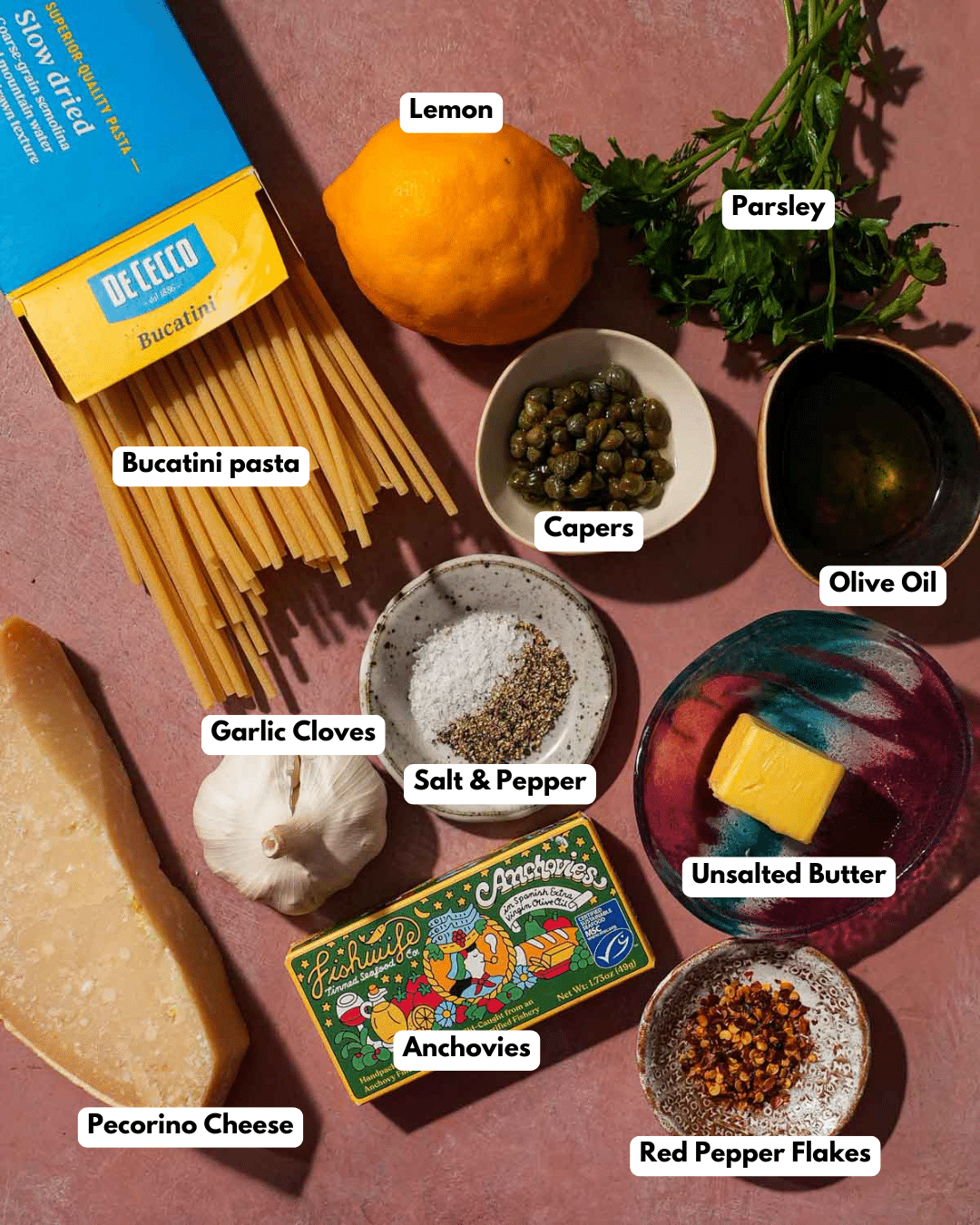 Ingredients for pasta: bucatini, lemon, capers, garlic, anchovies, butter, cheese, herbs, olive oil.