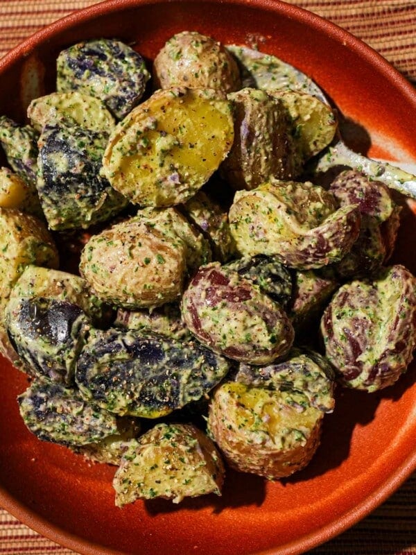 A bowl filled with potato salad with Chimichurri mayo with a spoon in it.