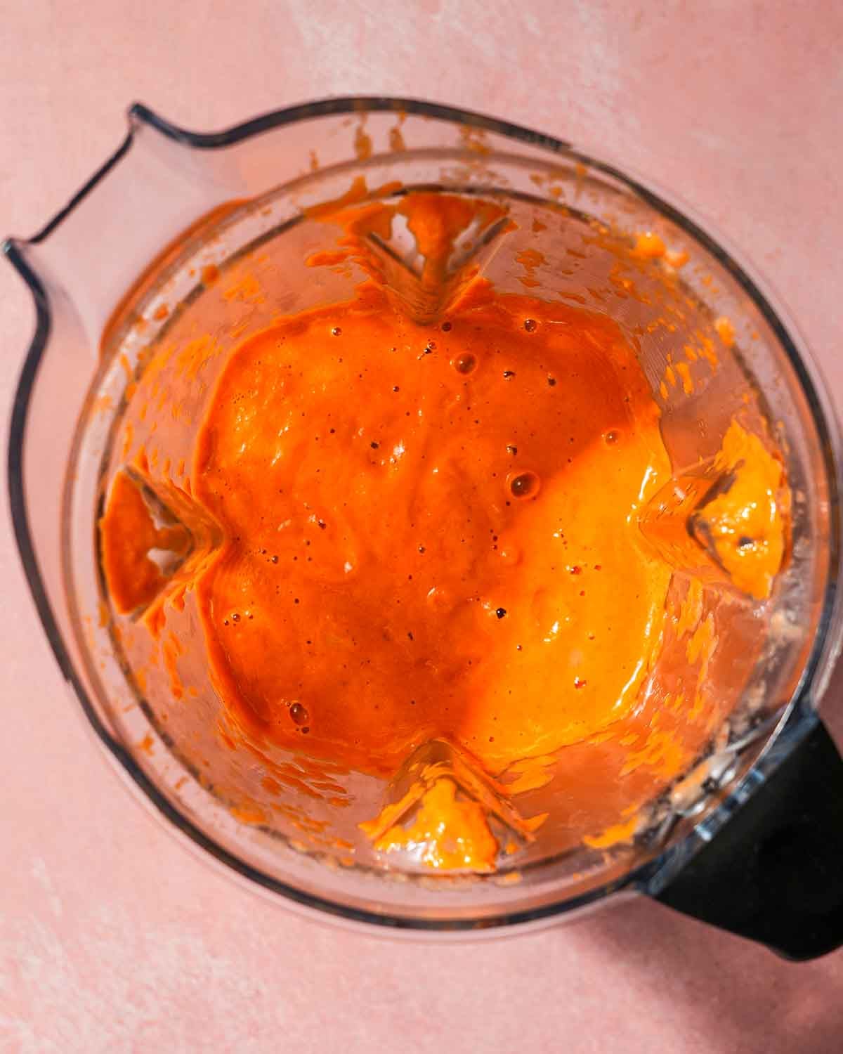 Inside of a blender of a mix of roasted red peppers and tomatoes for pasta sauce.