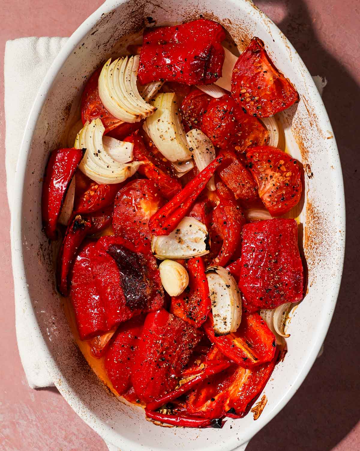 A white tray of roasted red peppers, tomato, garlic, and onion ready to be blended.