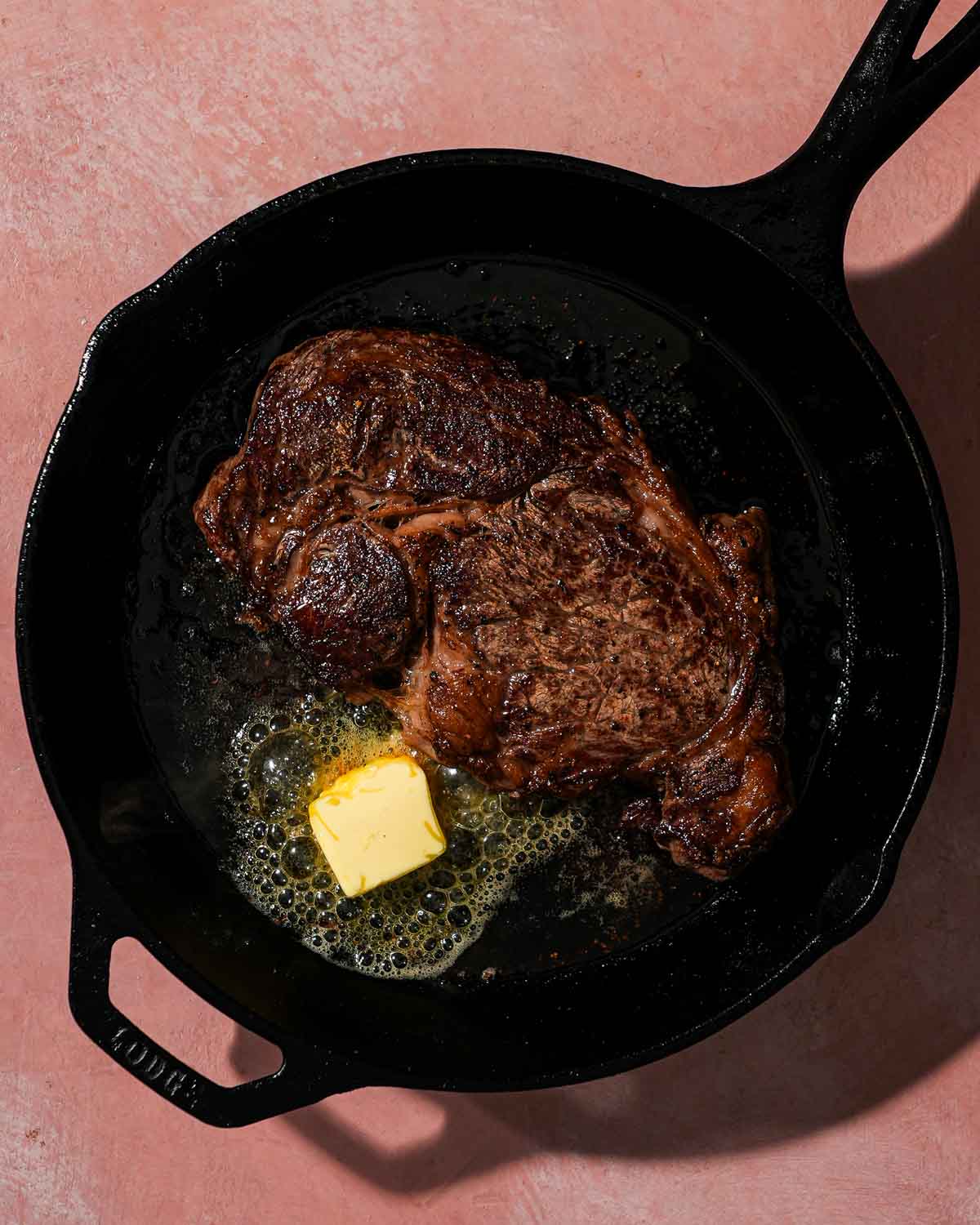 Cast iron with a seared ribeye and butter in it.