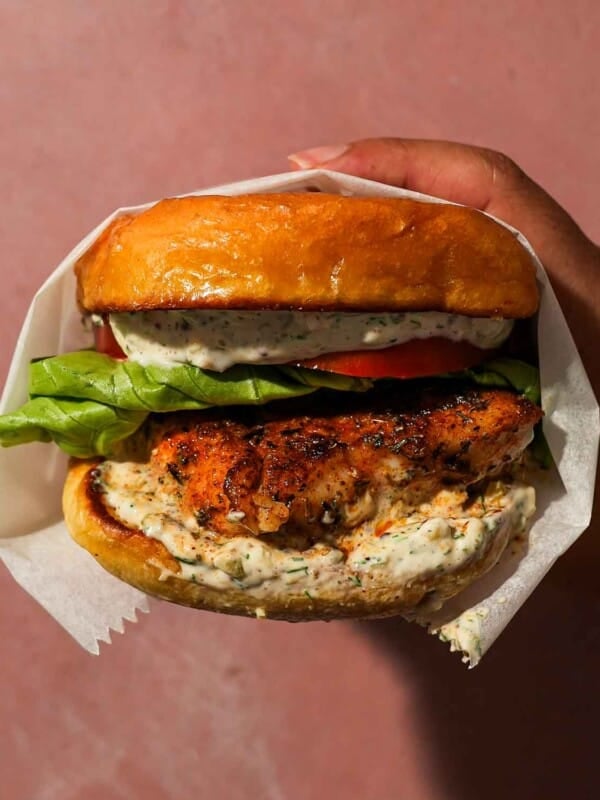 Blackened fish sandwich layered with lettuce, tomato, and creamy tartar sauce.
