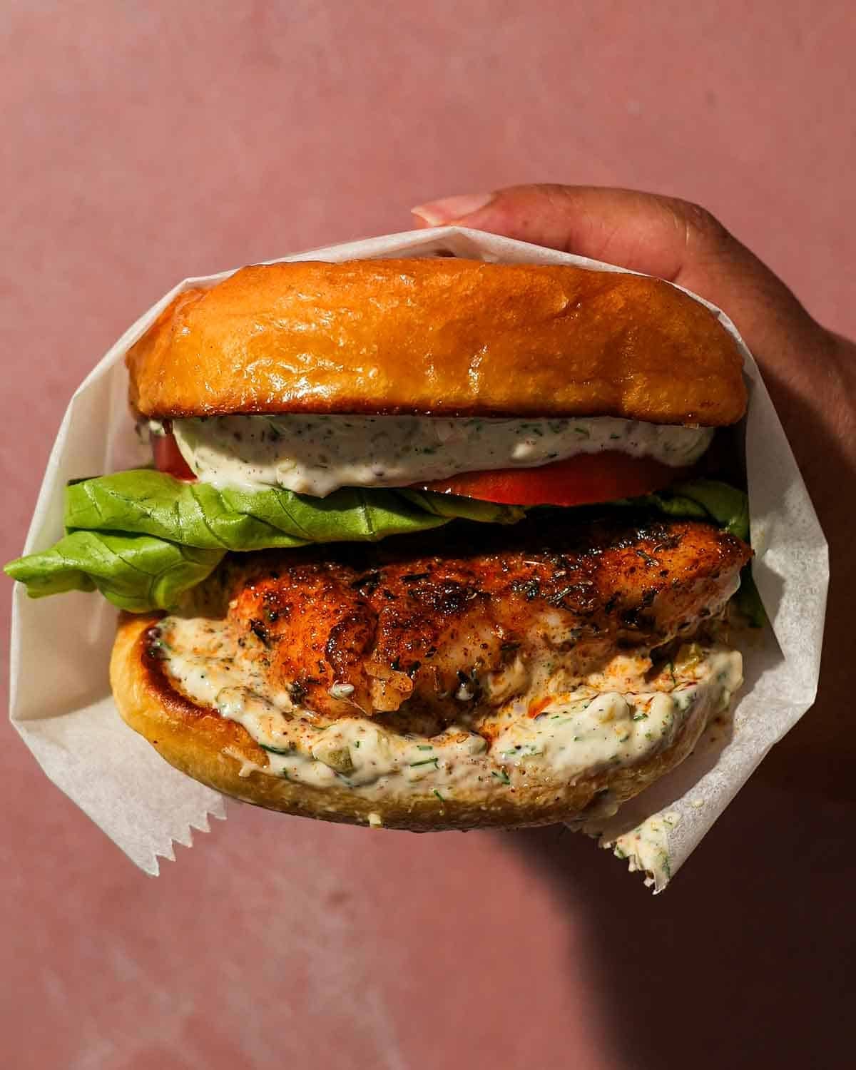 Blackened fish sandwich layered with lettuce, tomato, and creamy tartar sauce.