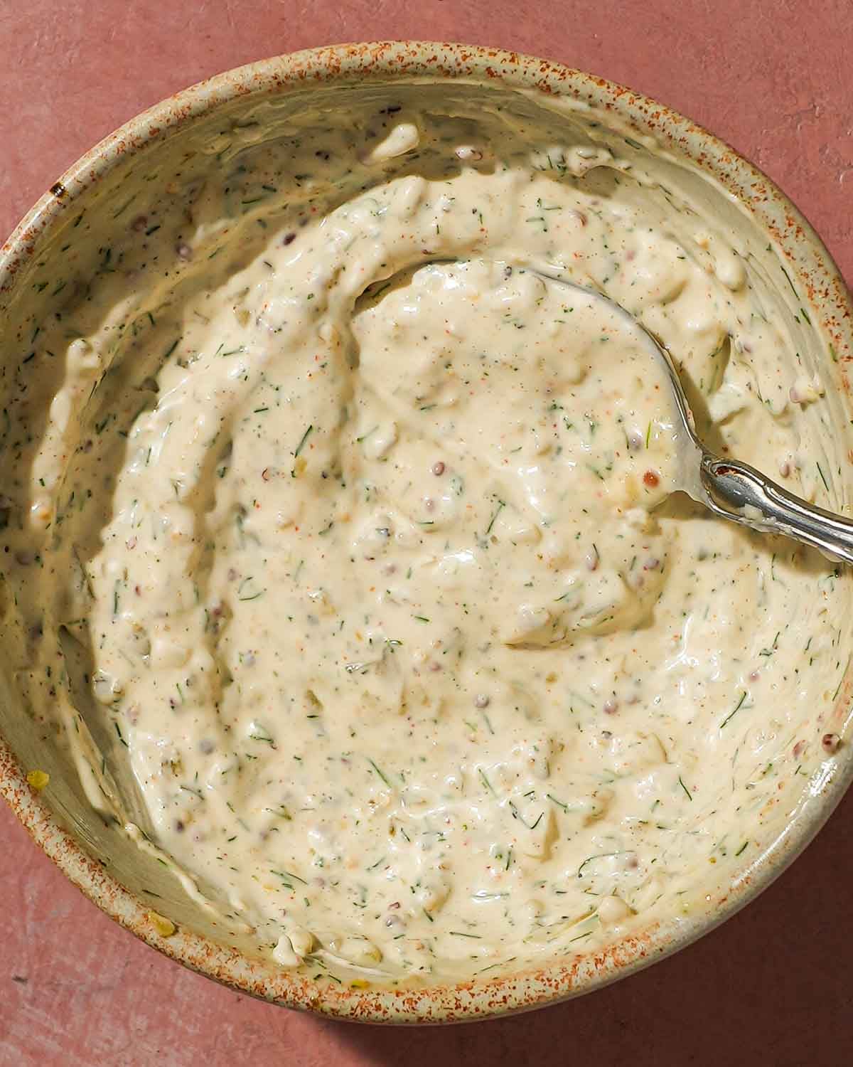 Bowl of homemade tartar sauce with herbs and seasonings mixed in.