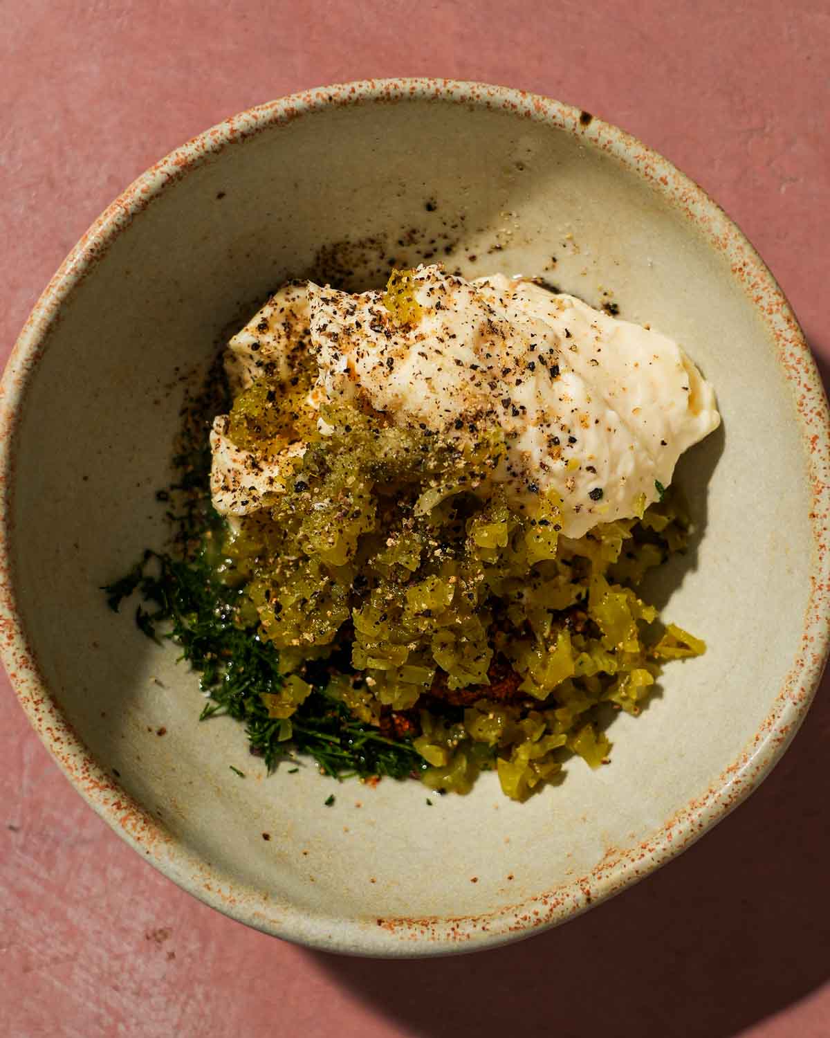Bowl of mayonnaise, relish, herbs, and spices before mixing tartar sauce.