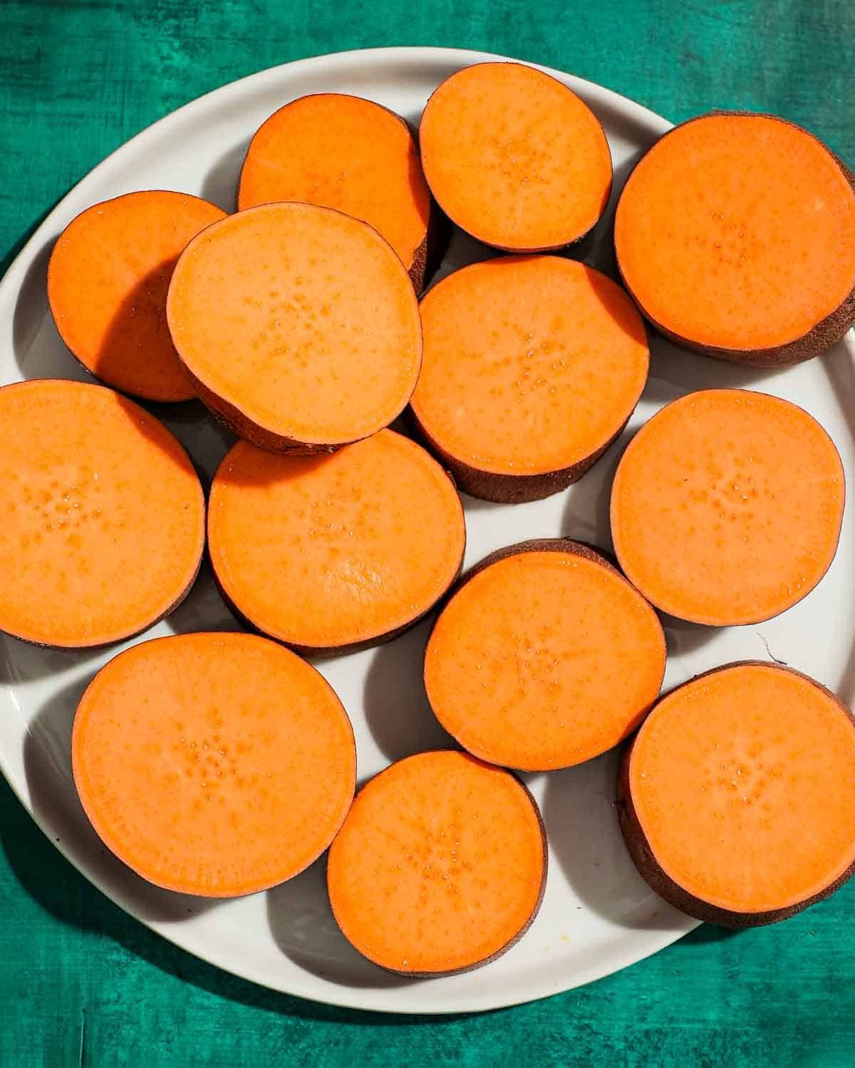A plate of sweet potato rounds on a blue background.