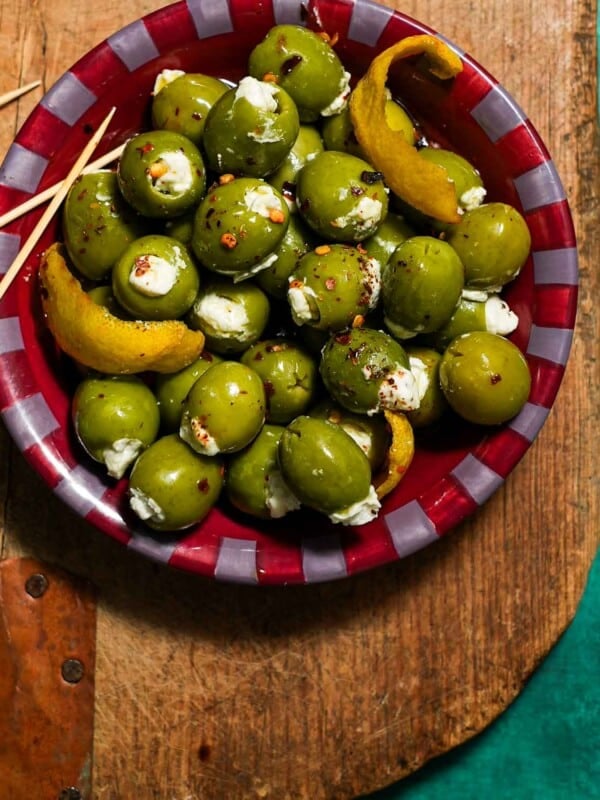 A bowl of blue cheese stuffed olives on a cutting board with toothpicks.