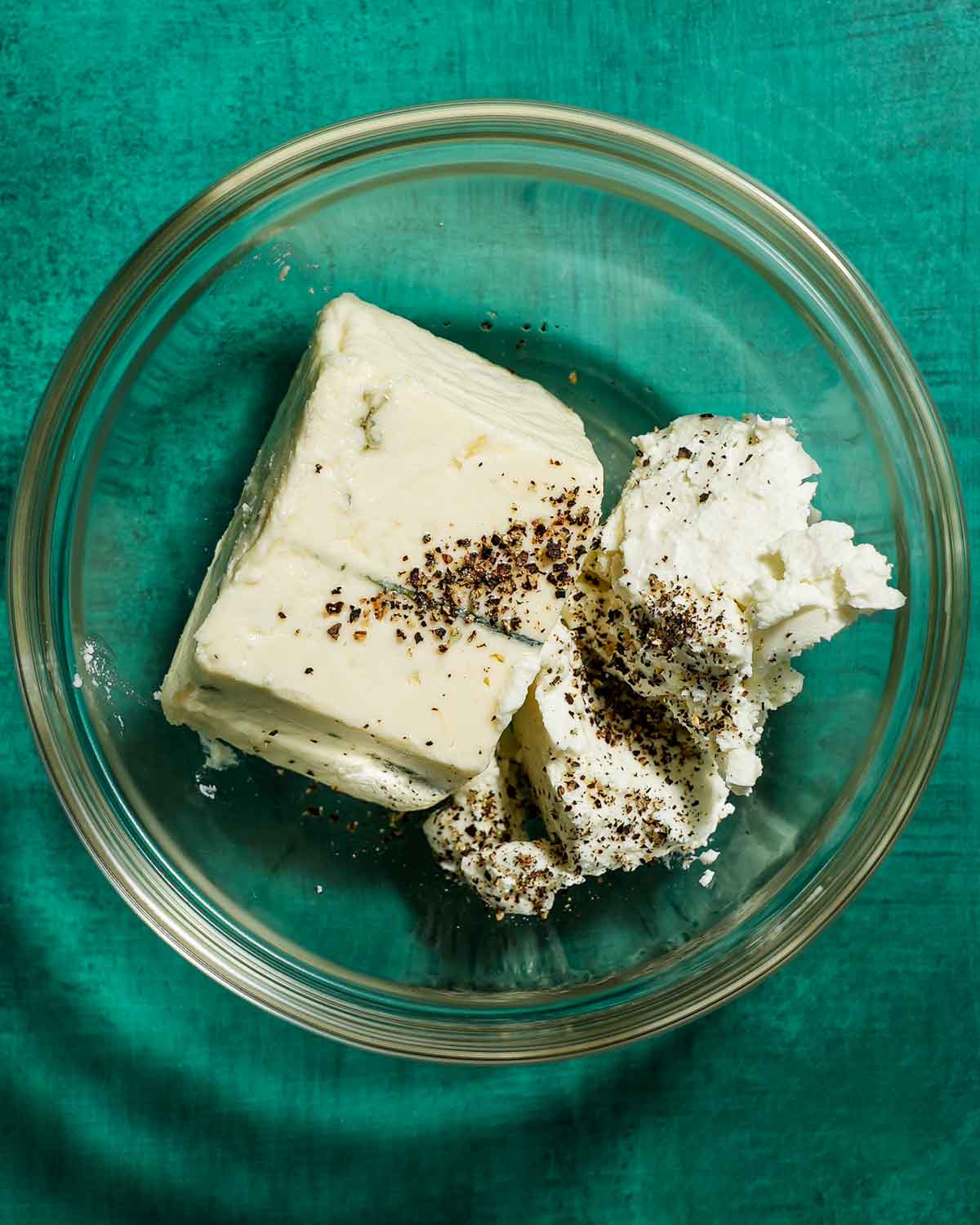 A bowl of blue cheese and goat cheese ready to be stuffed in green olives.