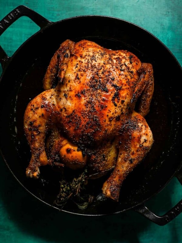 A cast iron with a whole roasted cooked chicken.