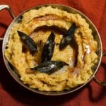 A bowl plated of brown butter mashed potatoes and sage.