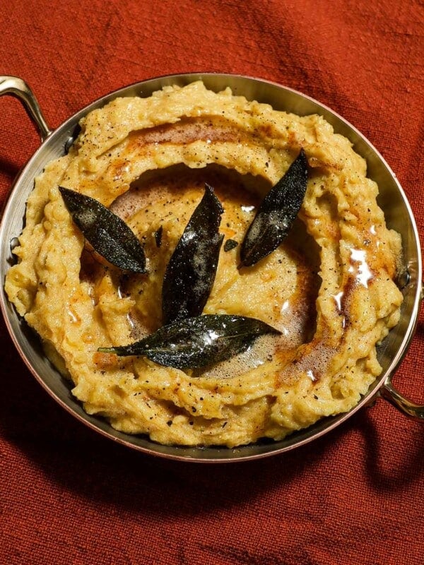 A bowl plated of brown butter mashed potatoes and sage.