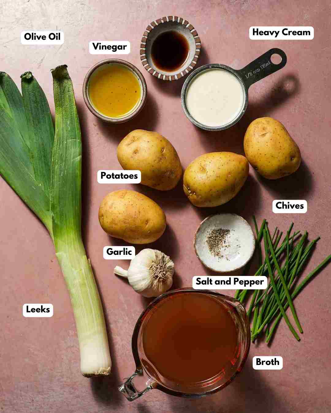 The ingredient laid out to make potato leek soup on a pink board.