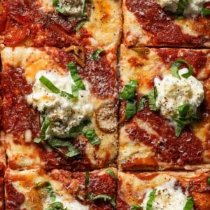Sheet pan pizza with burrata and hot honey cut into squares.