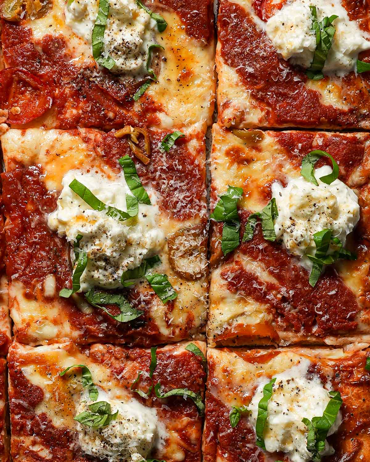 Sheet pan pizza with burrata and hot honey cut into squares.